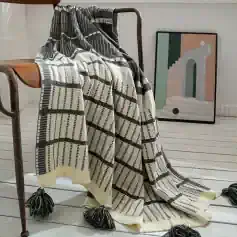 Luxurious black and white patterned throw blanket with tassels, perfect for home decor or cozying up in style.