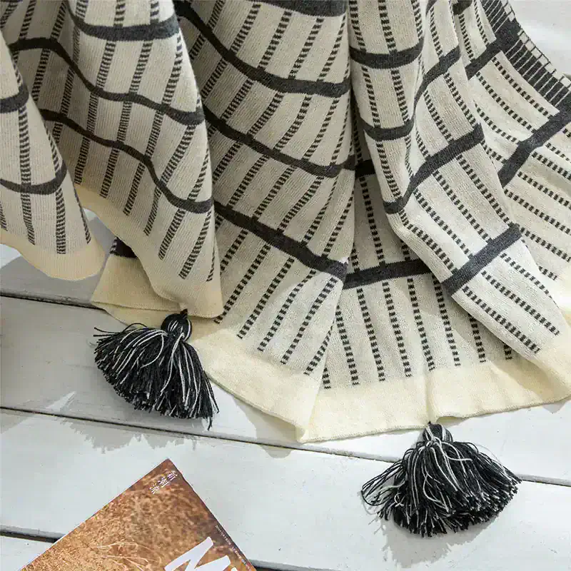 Luxury black and white striped woven throw blanket with tassels, perfect for cozy home decor and stylish accents.