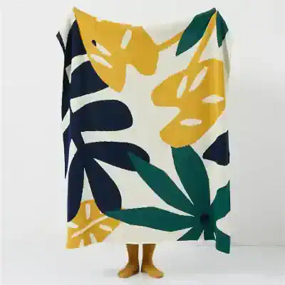Bright tropical print fabric featuring large botanical leaves in yellow, navy, and green, perfect for fashion or home decor, displayed on a mannequin with yellow legs.
