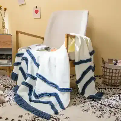 White and blue cozy throw blanket with tassels on a wooden armchair, modern home decor, Monalisa Medical store, stylish furniture, relaxed living space, comfortable textiles for home, contemporary interior accessories, elegant room design, bedroom or living room setup, decorative home accents.