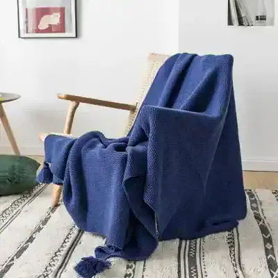 Luxurious blue throw blanket draped over a modern wooden armchair in a cozy living room, perfect for enhancing comfort and style.