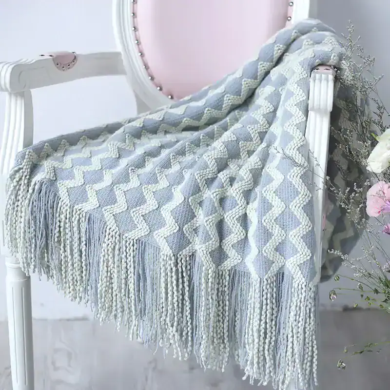 Soft gray and cream woven throw blanket with tassel fringe on a vintage-style white vanity table, ideal for cozy home decor and naps.