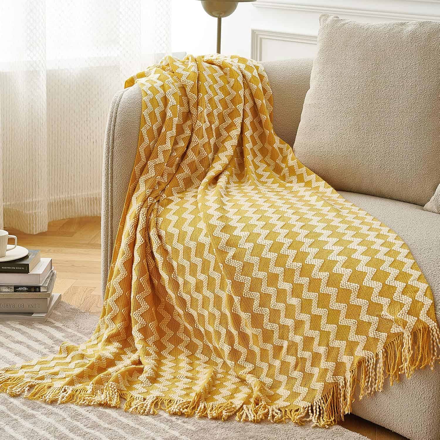 Vibrant yellow and white geometric patterned blanket draped over a beige sofa in a cozy living room setting. Perfect for adding color and style to your home decor.