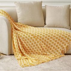 Soft beige sofa with a yellow and white zigzag patterned throw blanket and matching cushions, creating a cozy and stylish living space.