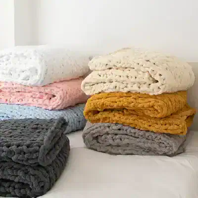 Luxurious plush blankets in various colors stacked on bed for cozy comfort and stylish decor. Perfect for home, bedroom, or sofa relaxation.