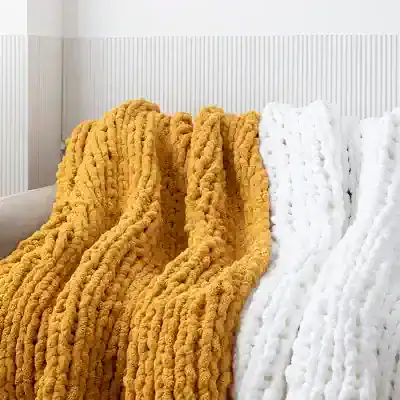 Soft plush blankets in mustard yellow and white, perfect for cozy bedroom decor or adding warmth to living spaces, displayed on a modern bed.