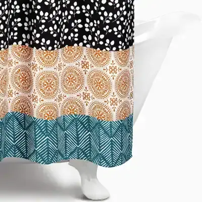 Black, white, and orange patterned shower curtain with floral and geometric designs on a white bathtub, emphasizing stylish bathroom decor.