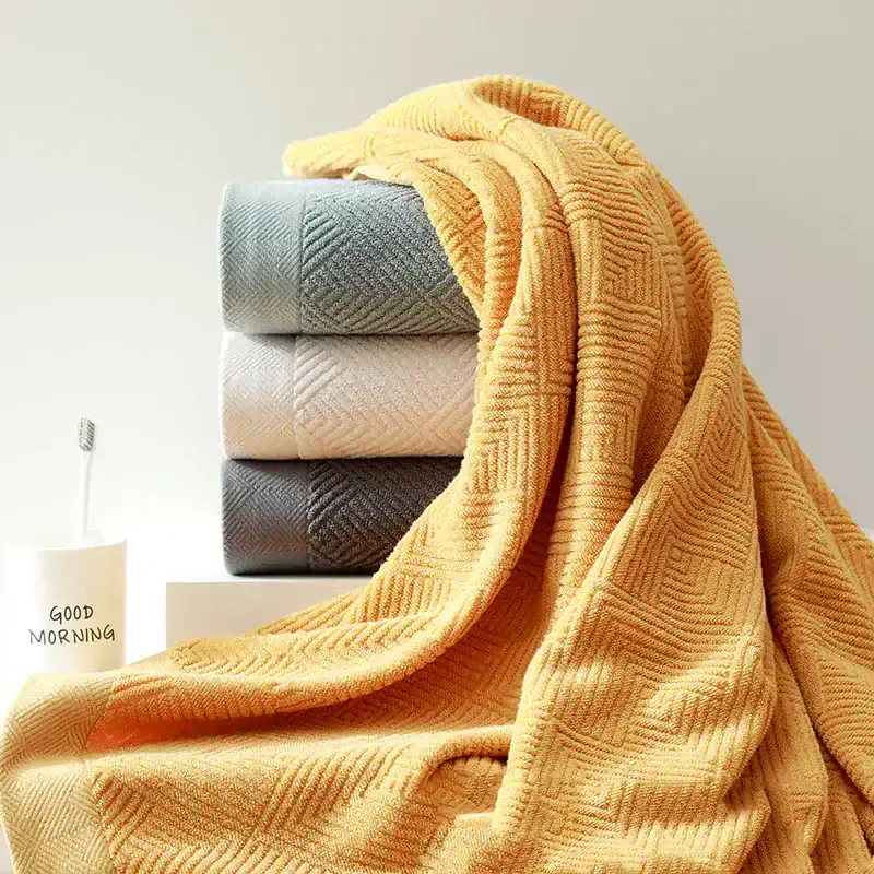 Soft, textured towels stacked in neutral colors with a cozy yellow blanket draped over for a comfortable, stylish bathroom setup – perfect for opt health and wellness spaces.