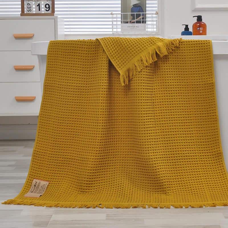 Soft yellow textured waffle knit throw blanket displayed over a white bathroom vanity, suitable for home decor, gifting, or everyday comfort, emphasizing cozy, stylish, and versatile interior accents.