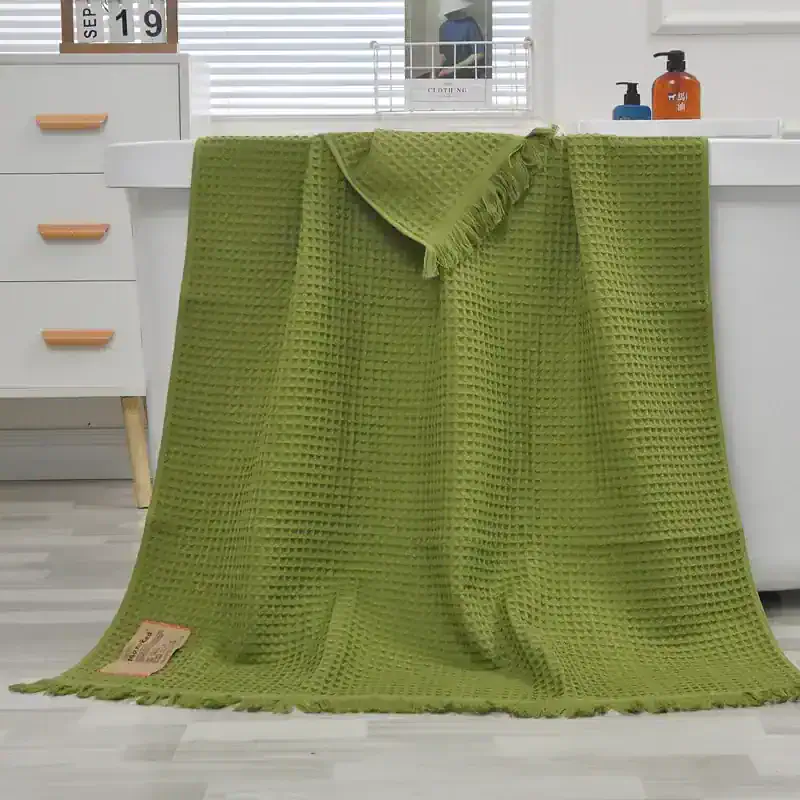 Green textured waffle weave bath towel for home and spa use.