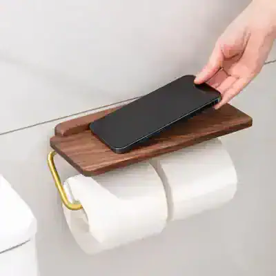 Wireless phone charging station on a wall-mounted wooden shelf with gold hooks, designed for convenient bedroom or bathroom use.