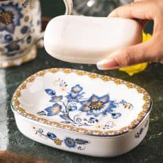 Colorful floral porcelain soap dish with a white bar of soap on top, featuring intricate blue and gold patterns, perfect for elegant bathroom decor and enhancing daily skincare routines.