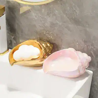 Shiny gold and iridescent decorative seashell-shaped containers on a white surface, perfect for elegant home decor or jewelry storage.