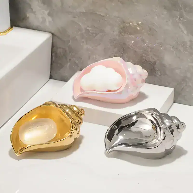 Shiny gold, silver, and pink seashell-shaped containers on a white surface, perfect for jewelry or small treasures, showcasing elegant home decor from Monalisa Medical Store.