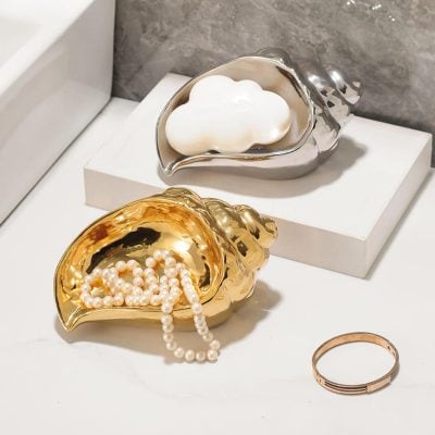 Luxurious pearl jewelry displayed in gold and silver clam-shaped containers, elegant accessories for fashion and special occasions, available at Monalisa Store for optimal style and elegance.