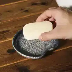 Bar of soap on a black and white textured dish at Monalisa Store, skincare, luxury soap, natural ingredients, wellness products, boutique spa essentials, elegant hygiene accessories, premium toiletries, organic skincare, beauty and health products.