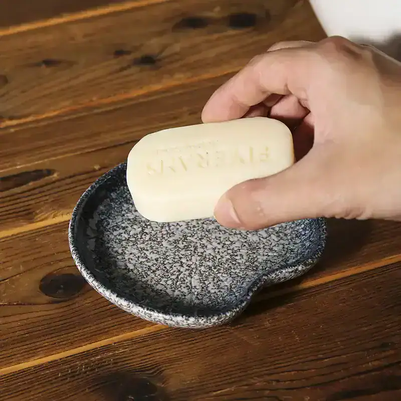 Bar of soap on a black and white textured dish at Monalisa Store, skincare, luxury soap, natural ingredients, wellness products, boutique spa essentials, elegant hygiene accessories, premium toiletries, organic skincare, beauty and health products.