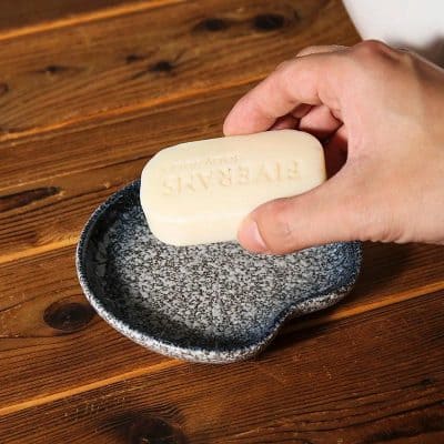 Luxury natural soap bar with embossed branding on rustic ceramic dish for skincare and wellness.
