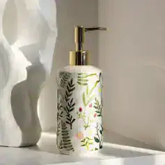 White floral patterned liquid soap dispenser with gold pump on a light-colored surface. Perfect for bathroom or kitchen decor, combining elegance and nature-inspired design.