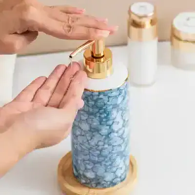 Luxury soap dispenser with gold accents and blue marble design, ideal for skincare or beauty routines.