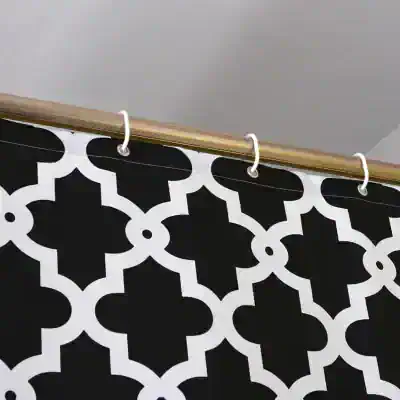 Black and white geometric patterned shower curtain hanging on a brass rod at Monalisa Store, designed for modern bathroom decor and stylish home accessories.