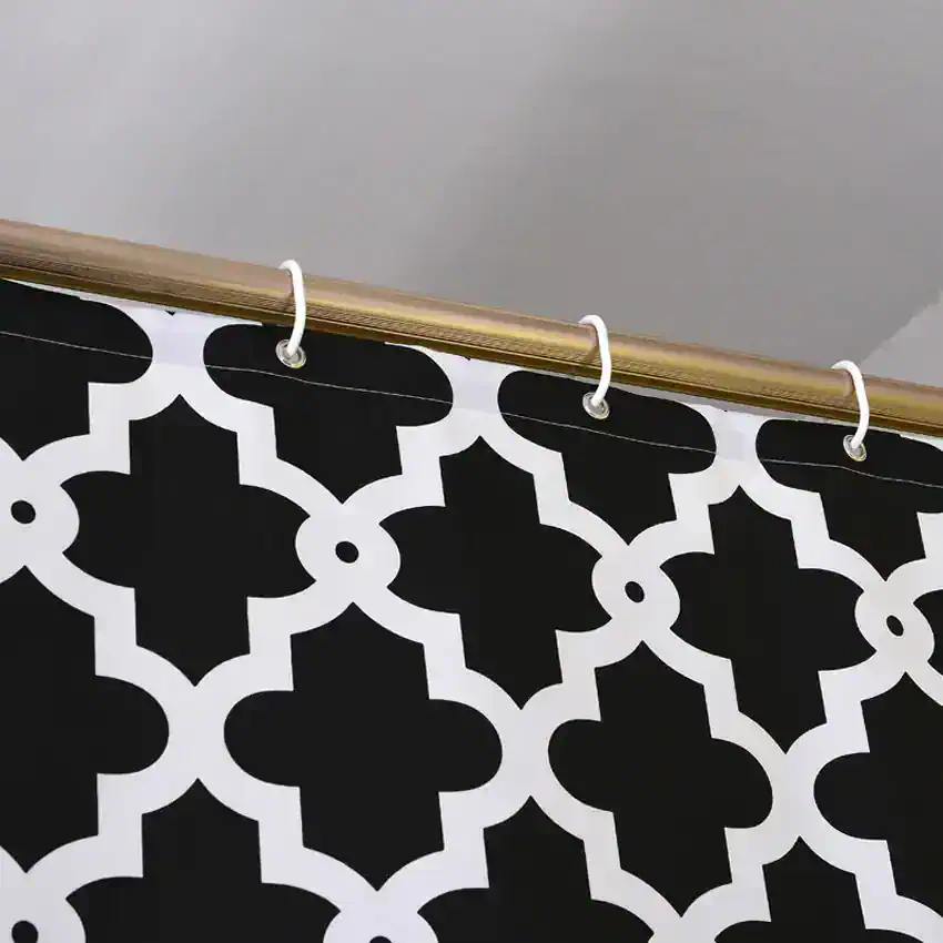 Black and white geometric patterned shower curtain hanging on a brass rod at Monalisa Store, designed for modern bathroom decor and stylish home accessories.
