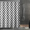 Vibrant black and white geometric shower curtain in modern bathroom with rain shower head and gray tiled walls.
