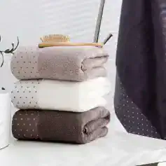 Luxury towels stacked with a wooden bath brush and grooming tools, elegant bathroom accessories, soft and plush texture, Monalisa Store home spa essentials, modern and stylish bathroom decor, high-quality textile products, wellness and self-care items for a comfortable home environment.