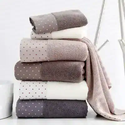Soft plush towels in neutral colors stacked on a white surface with a minimalist background.