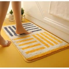 Modern geometric bathroom rug with yellow and navy blue stripes, soft plush texture, perfect for enhancing bathroom decor and providing comfort underfoot.