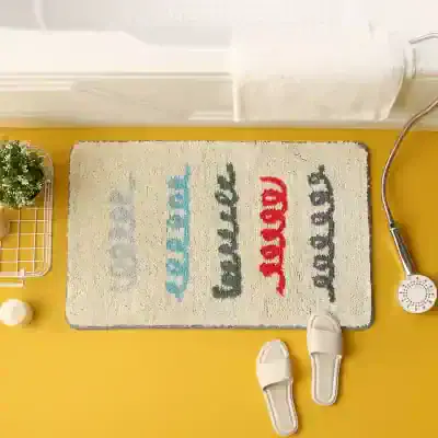 Bright yellow bathroom floor with a beige rug that has colorful text, a shower head, and slippers, emphasizing an inviting, modern look in an optometry store setting.