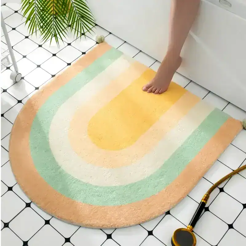 Colorful rainbow bath rug on white tiled floor, soft plush design for bathroom decor and comfort, featuring pastel shades of peach, mint, yellow, and cream. Perfect for enhancing bathroom aesthetics and adding cozy touch.