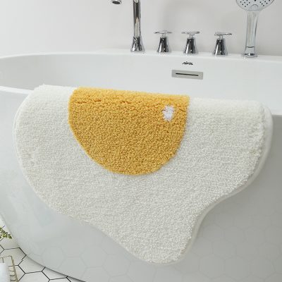 Soft plush bath rug in front of bathtub, plush bath mat with yellow and white colors for bathroom decor, non-slip and absorbent bathroom rug, perfect for spa and relaxing baths, Monalisa Medical bathroom accessories.