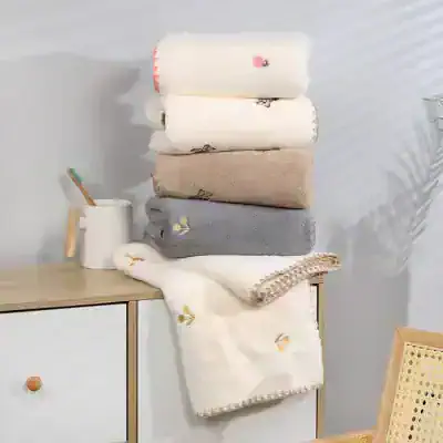 Soft pastel towels with floral embroidery and textured accents at Monalisa Store, perfect for optometry and eyewear styling, displayed on a minimalist wooden surface.