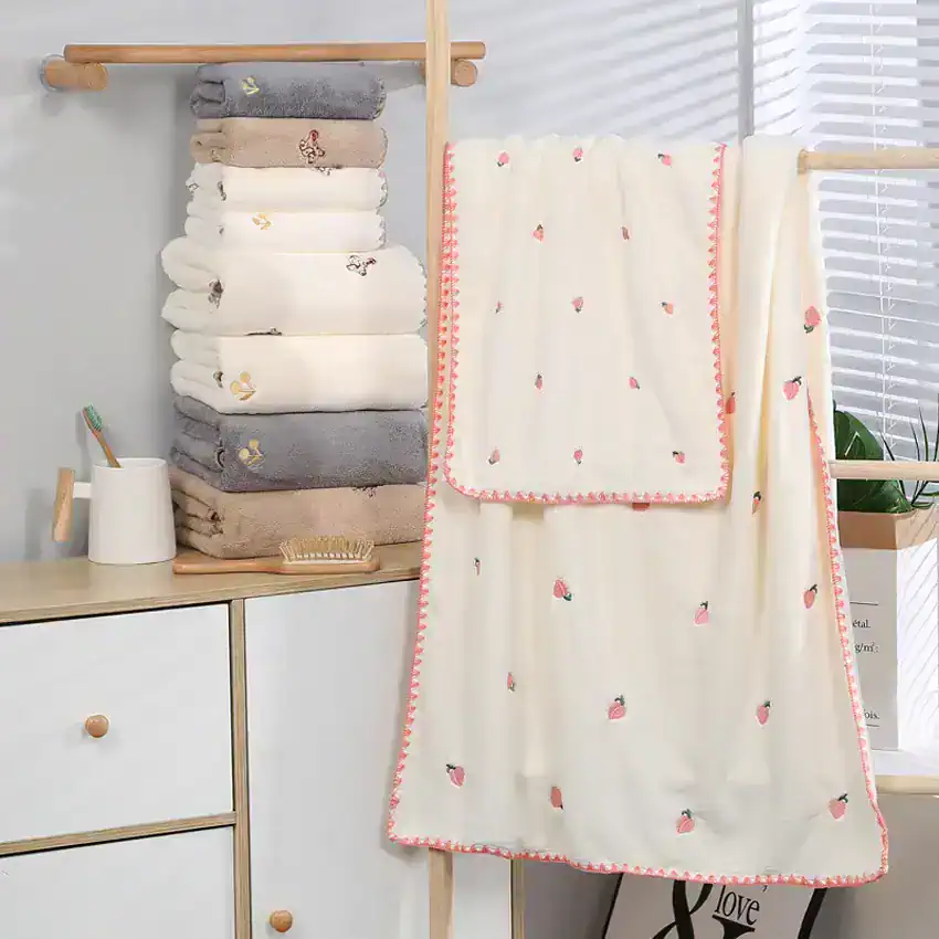 Soft plush towels and cozy embroidered blanket with pink accents displayed in modern bathroom setting for home comfort and luxury.