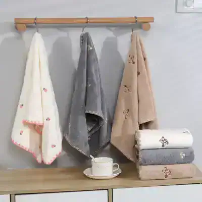 Soft plush towels with cute embroidery patterns hanging on a wooden rail in a modern bathroom decor, ideal for a cozy and stylish upgrade.