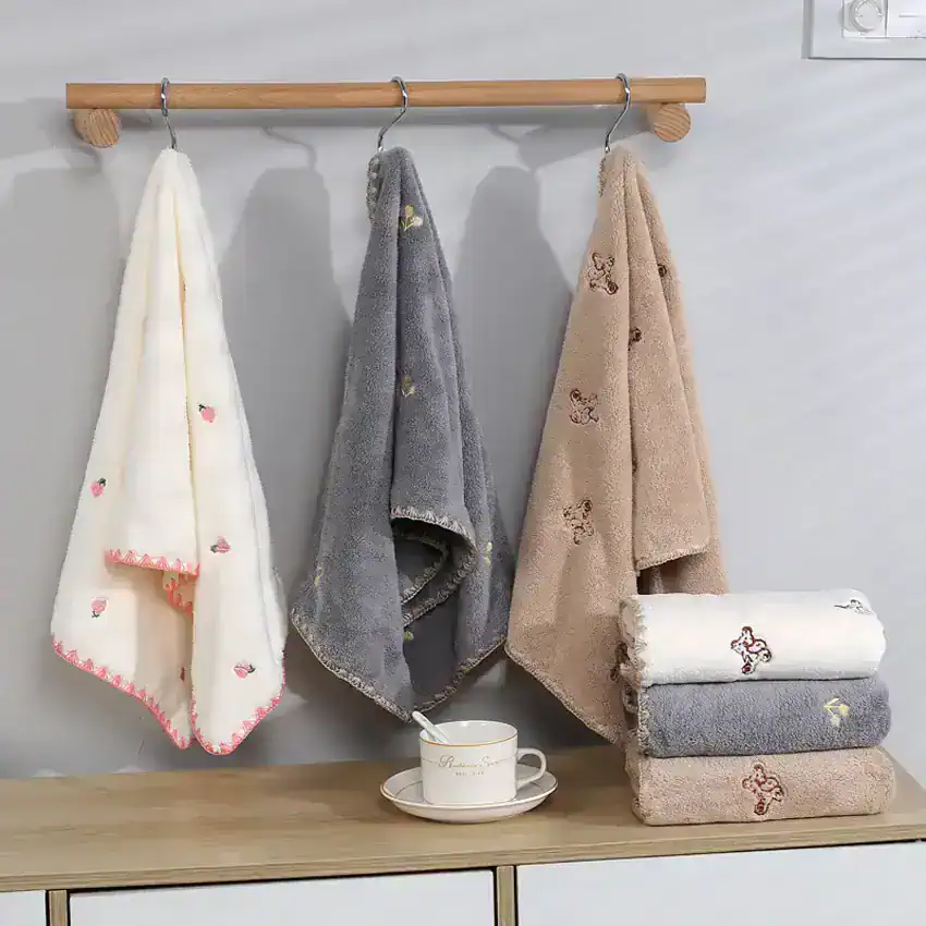 Soft plush towels with cute embroidery patterns hanging on a wooden rail in a modern bathroom decor, ideal for a cozy and stylish upgrade.
