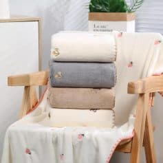 Soft plush towels in pastel colors with embroidered details displayed on a wooden chair for luxurious home and bathroom decor. Perfect for premium towel collections.