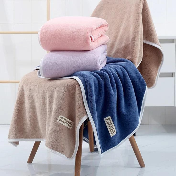 Luxurious plush towels in soft pink, lavender, and navy blue displayed on a modern chair for home or spa use, promoting comfort and relaxation.