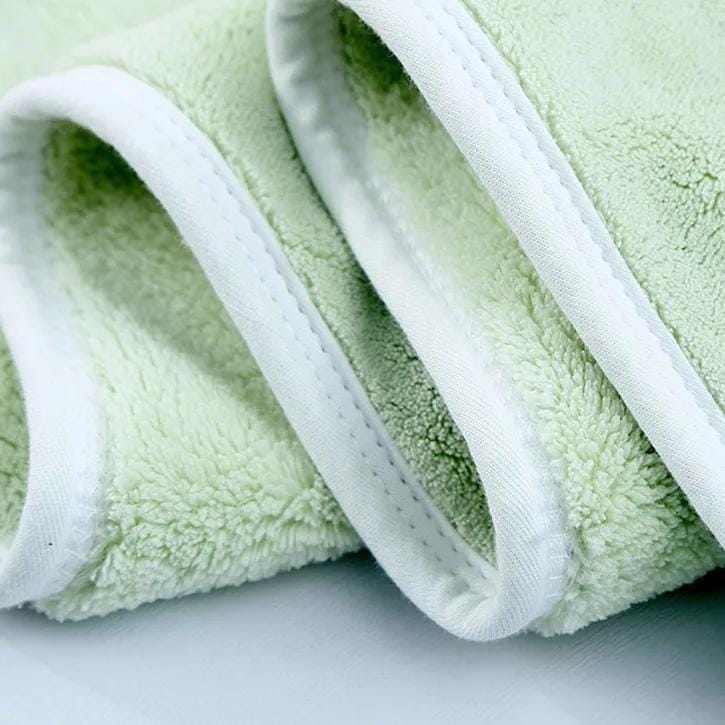 Fluffy green terry cloth towel with white trim, close-up detail, soft and plush fabric for skincare or spa use.