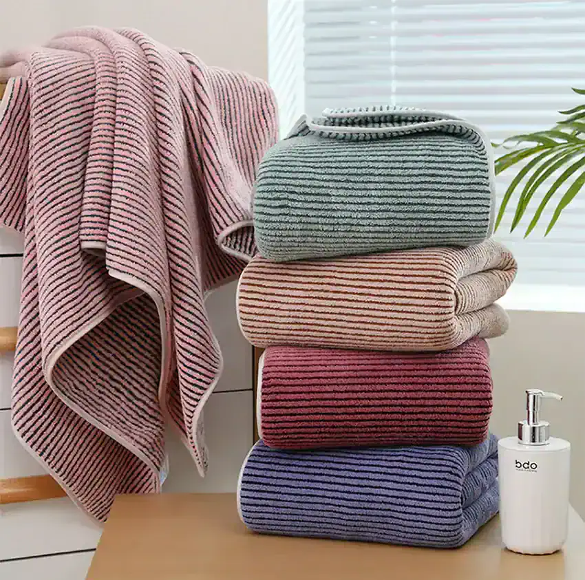Soft, striped towels and blankets displayed in a cozy home setting at Monalisa Store, perfect for bath or bedroom decor, emphasizing comfort and quality textiles for premium home essentials.