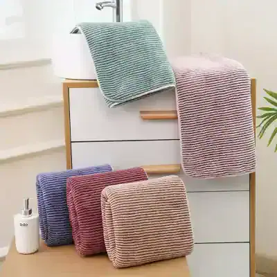 Striped bathroom towels and accessories on a modern storage cabinet, promoting Monalisa Medical's premium bath linens and wellness products for a luxurious home spa experience.