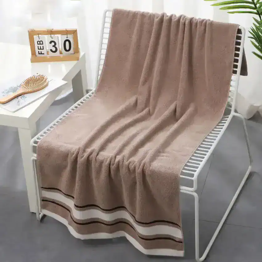 Luxurious beige towel draped over a modern white bench, perfect for spa or bathroom decor, emphasizing comfort and style.