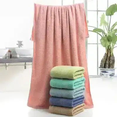 Soft pastel-colored bath towels stacked in a bright, modern bathroom with large windows and a potted plant, emphasizing comfort and luxury in personal hygiene.