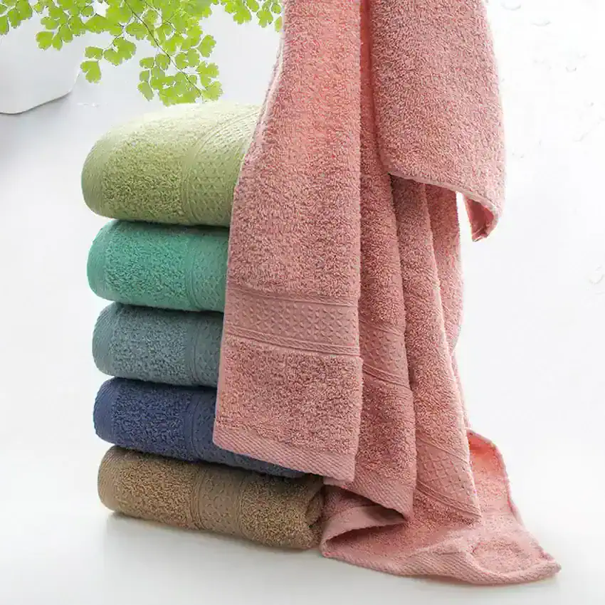 Soft pastel-colored bath towels stacked, with a pink towel draped over the top, in a bright, clean setting. Perfect for spa, hotel, or home use, emphasizing comfort and luxury.