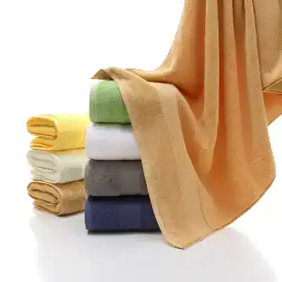 Colorful soft towels stacked in various shades including peach, yellow, white, gray, navy, and green, ideal for luxury spa and beauty salons.