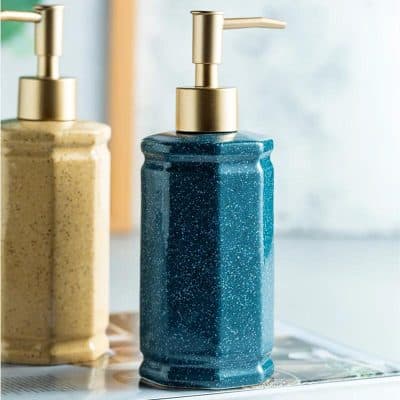 Vegan soap dispenser with gold pump on marbled blue ceramic countertop at Monalisa Store.