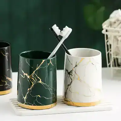 Green and white marble pattern toothbrush holders with gold accents, perfect for modern bathroom decor. Stylish storage solutions for toothbrushes and toothpaste.