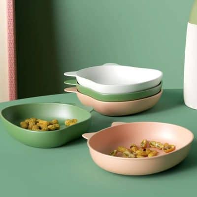 Colorful eco-friendly recycled melamine bowls stacked and filled with snacks, used in modern kitchen or dining settings.