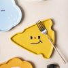 Yellow smiley face fish-shaped plate with a fork on it, playful tableware design for kids and families.